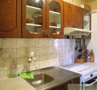 A kitchen in a cottage with a stylish wooden cabinet, white tiles, and kitchen accessories.