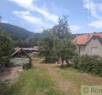 A country house surrounded by a garden and trees, with hills and vineyards in the background.
