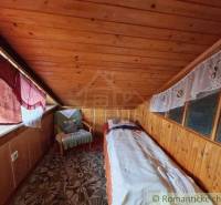 In this cozy cabin, there is a wooden room with a bed and a chair by the window.