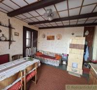 A traditional room interior with old furniture, paintings, and a ceramic stove in a cottage.