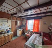 A traditional kitchen in a cabin with wooden paneling and vintage decorations.