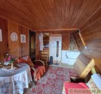 A cottage with wooden cladding, a tiled stove, and flowers on the table. A romantic cottage.