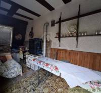 A room in a cottage with a floral tablecloth and retro decorations on a wooden shelf.