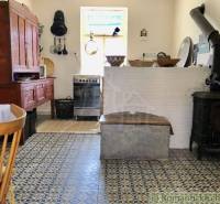 A country kitchen in a family house with antique furniture, a stove, and patterned tiles.