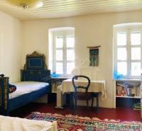 A room with retro furniture, a carpet, an armchair, and a family house emphasizing a rural atmosphere.