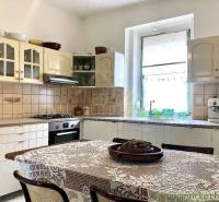 A kitchen in a family house with a wooden table, ceramic tiles, and a gas stove.