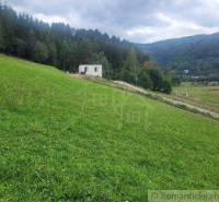 A house on a slope, surrounded by forest and gardens, offers a peaceful natural environment.