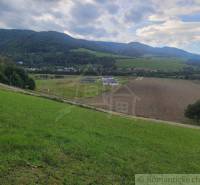 A beautiful landscape with fields and gardens, surrounded by green hills and a village.