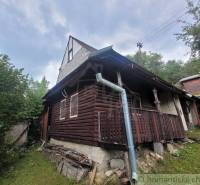 Traditional log cabin with a porch in the forest, ideal for a family home.