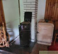 In the room of a family house, an antique spinning wheel, a stove, and a historical refrigerator by the wall.