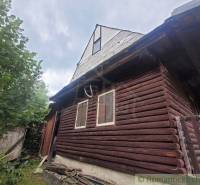 A wooden cottage with a wooden fence and shutters, set in green nature. Family house.