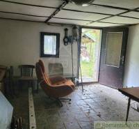 The interior of a family house with an old armchair, open doors, and a rustic appearance.