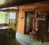 Rustic interior of a cottage with wood, a stool, a table, and glasses in a family house.