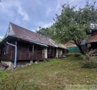 An old wooden family house with a gable roof and a fruit tree in the garden.