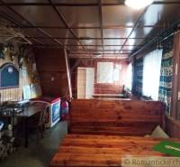 The interior of a wooden cabin with benches and a map, immersed in a rural setting.