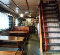 In a cozy cabin with wooden tables and a staircase, there is a bar with drinks and snacks.