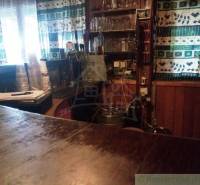 Interior of the cabin, wooden paneling, window curtains, drinks, and shelves with glasses.