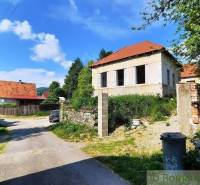A nice family house for renovation, surrounded by trees, road, trash bins.
