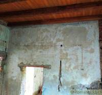 The worn plaster in the old family house, cracks on the walls, and a ceiling made of beams.