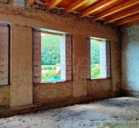Interior of a building with brick walls, a wooden ceiling, and a view of nature.