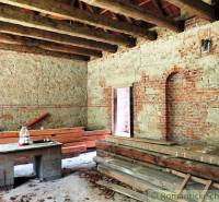 The interior of an old family house with raw walls and a beamed ceiling, ready for renovation.