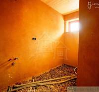 Interior of a family house with clay walls, a wooden ceiling, and preparation for installations.