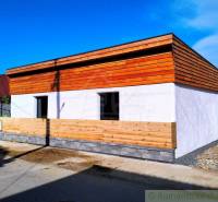 A family house with wooden cladding and a white facade on a quiet street.