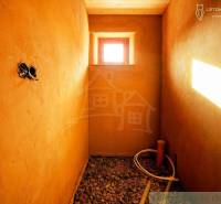 Interior with clay walls, a window, round piping, and a pebble floor, suitable for a family house.