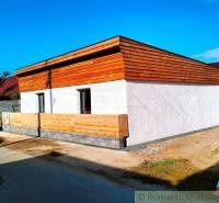 Family house with wooden cladding on the facade, fencing combined with concrete.