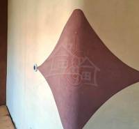 On the wall of the family house, there is a clay decoration with an elegant ornament and a stream of light.