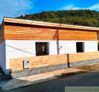 A family house with wooden elements on the facade surrounded by a natural environment and a blue sky.
