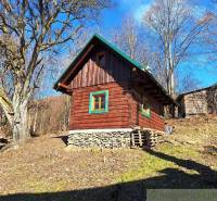 A wooden cabin in the forest, surrounded by trees and sunlight, ideal for relaxation.