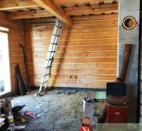 Attic cabin with wooden interior, ladder, and building materials in the room.