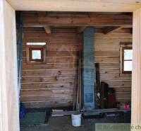 The interior of a wooden cabin with a brick chimney and wooden floor in the countryside.