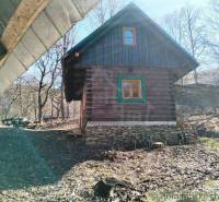 A wooden cabin surrounded by forest and a picnic table create a peaceful natural atmosphere.