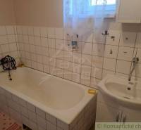 The bathroom contains a bathtub and a sink with tiles in a family house.