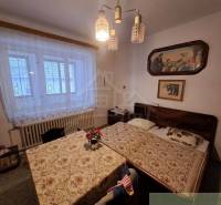 A bedroom in a family house with two beds, paintings, and a decorative chandelier.