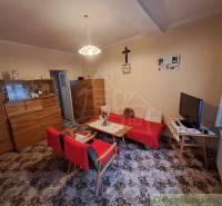 Living room in a family house with a wooden wall, red couch, and television.