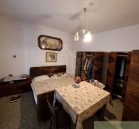 A bedroom with wooden furniture, a bed, and flowers in a family house creates a cozy atmosphere.