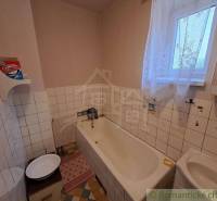 Family house bathroom with a bathtub, sink, window, and patterned floor.