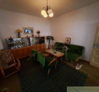 Living room in a family house, contains an old display cabinet, a sofa, and a carpet.