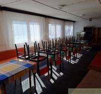 Interior with commercial spaces, tables and chairs overturned on colorful tablecloths.