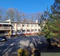 A residential building surrounded by trees and parking spaces, suitable for commercial premises.