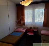 A room with beds, curtains, and a table, ideal for simple commercial spaces.