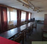 A room with long tables, chairs, and a window; ideal for business spaces.