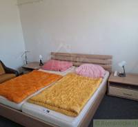 Simple bedroom with a bed, nightstands, an armchair, and reading lamps.