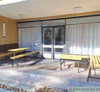 Entrance commercial spaces with wooden benches and tables on the terrace under a shelter.