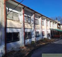 A two-story building with a repairable facade and seating areas near commercial spaces.