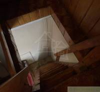 Wooden stairs to the attic in the cottage, with a wooden paneled wall.
