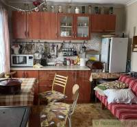 We see a kitchen with a wooden kitchen unit in a cabin, with a dining table.